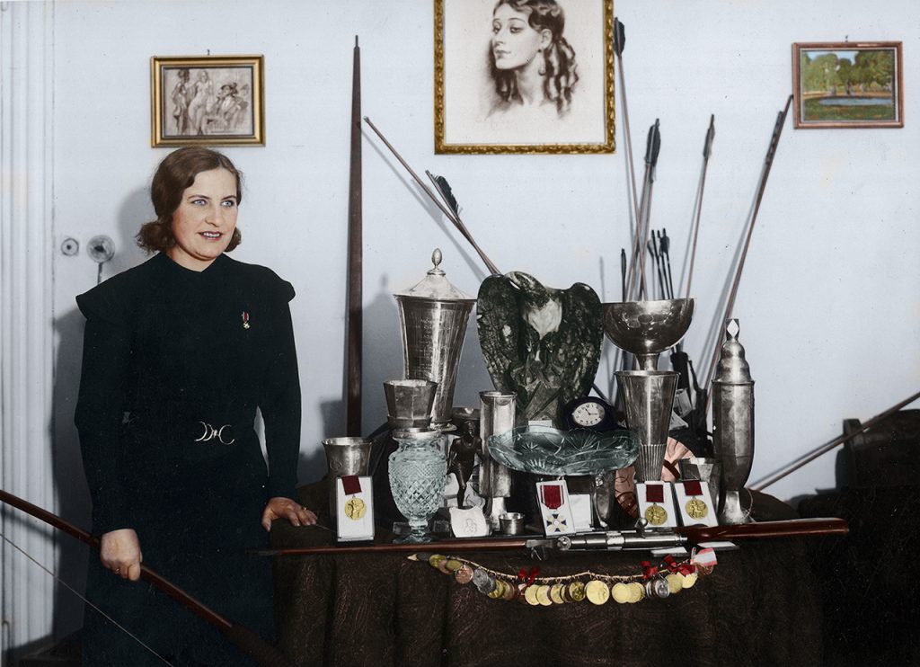 Łuczniczka Janina Kurkowska-Spychajowa prezentuje zdobyte trofea sportowe. Zdjęcie zostało wykonane w 1934 r. Za pięć lat, na kilka miesięcy przed wybuchem wojny, mistrzyni odda sportowe pamiątki, by zasilić budżet polskiego lotnictwa Fot. NAC